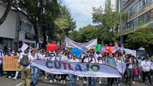 Multitud marchando, con un cartel grande que tiene las letras CUTLAJO