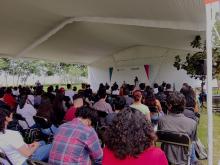 Estudiantes de nuevo ingreso sentadxs, mirando hacia el podio.