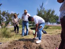 Alumno arando tierra en el huerto estudiantil