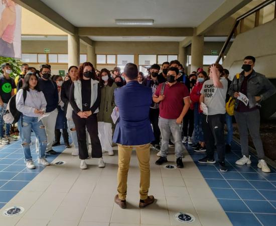 Espalda de un profesor y grupo de estudiantes de la carrera de Negocios Internacionales detras.