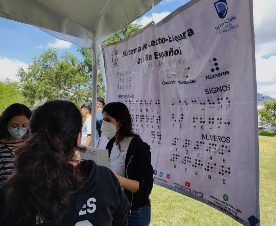 Estudiantes partcipando en actividad de la DDU, con un abecedario en braile de fondo