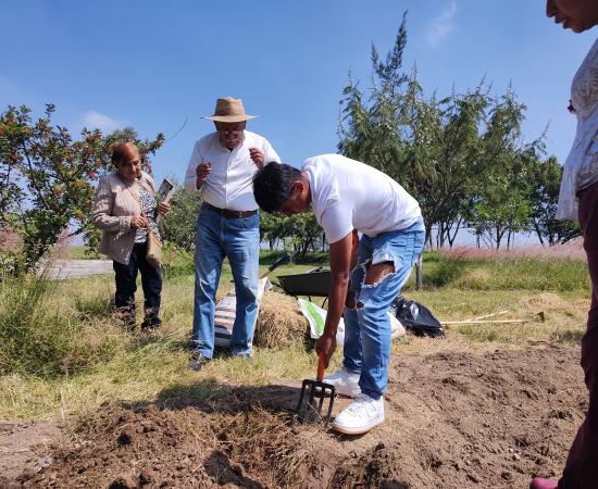 Alumno arando tierra en el huerto estudiantil