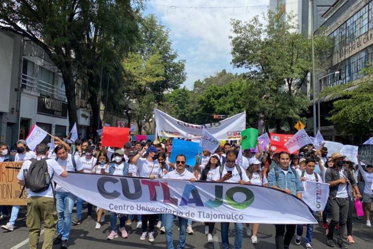 Multitud marchando, con un cartel grande que tiene las letras CUTLAJO