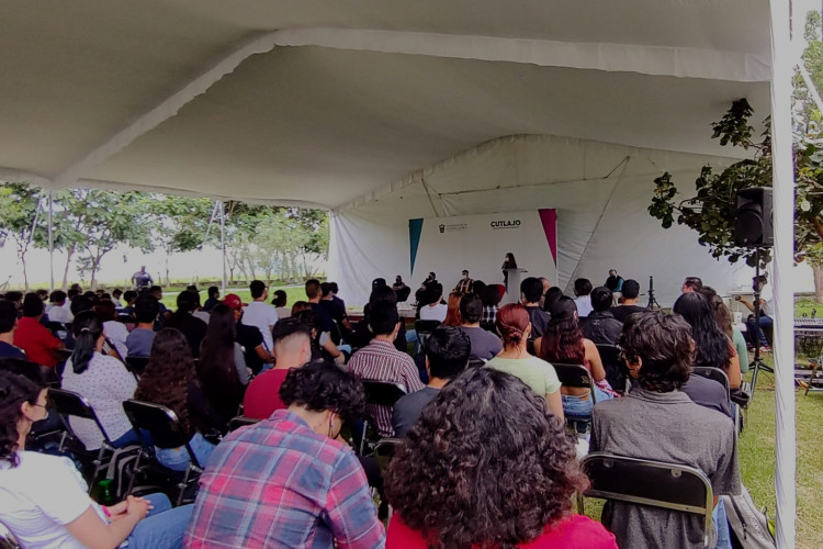 Estudiantes de nuevo ingreso sentadxs, mirando hacia el podio.